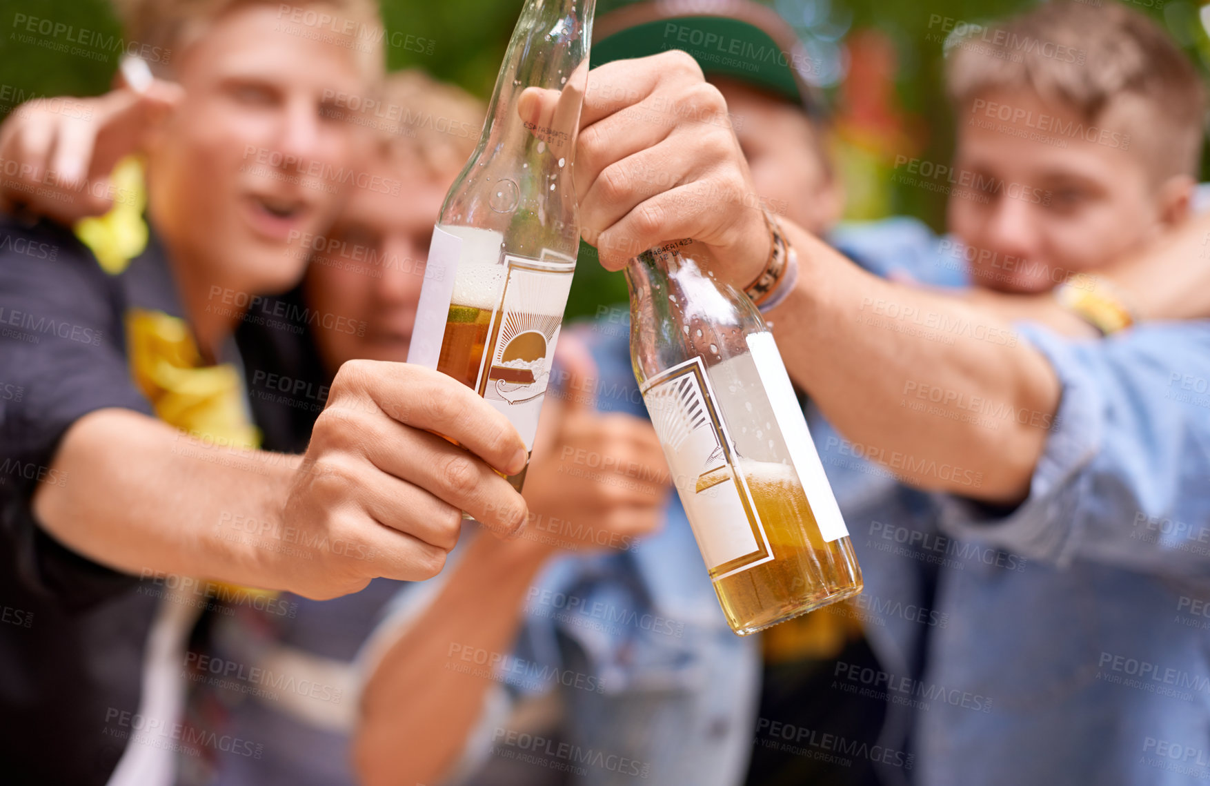 Buy stock photo Cropped shot a group of young men toasting with beer bottles