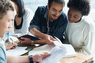 Buy stock photo Shot of a study group going over work in their textbook