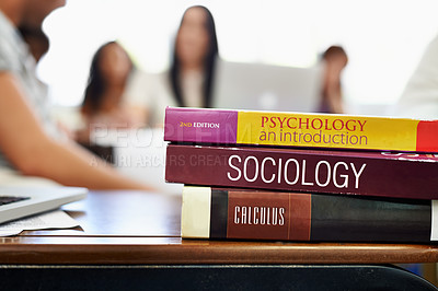 Buy stock photo Cropped shot of university text books on a desk with students blurred in the background
