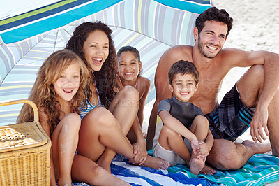 Buy stock photo Happy family, beach and relax for bonding, vacation or outdoor holiday weekend together. Dad, mom and children or kids smile by umbrella for love, support or summer break by ocean coast in nature