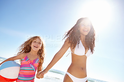 Buy stock photo Happy mother, child and beach ball in sun for fun summer holiday, bonding or playing in nature. Mom holding hands with daughter or playful kid smile on weekend vacation by the ocean coast in sunshine