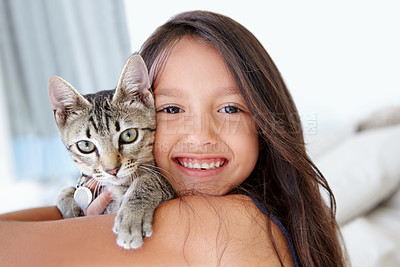 Buy stock photo Smile, cat and portrait of child at her home cuddling, hugging and bonding with her animal. Happy, love and face of young girl kid embracing her kitten pet with care in living room of family home.