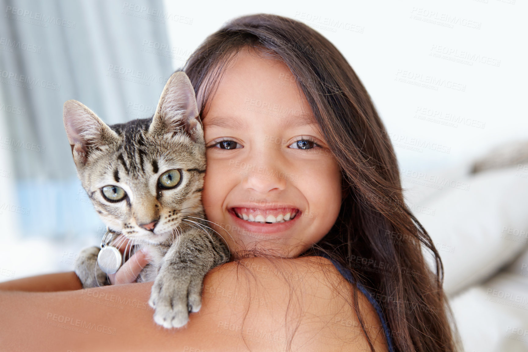 Buy stock photo Smile, cat and portrait of child at her home cuddling, hugging and bonding with her animal. Happy, love and face of young girl kid embracing her kitten pet with care in living room of family home.