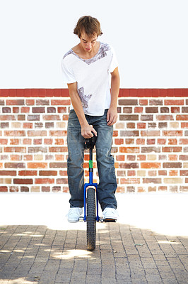 Buy stock photo Full-length shot of a young man balancing on a unicycle