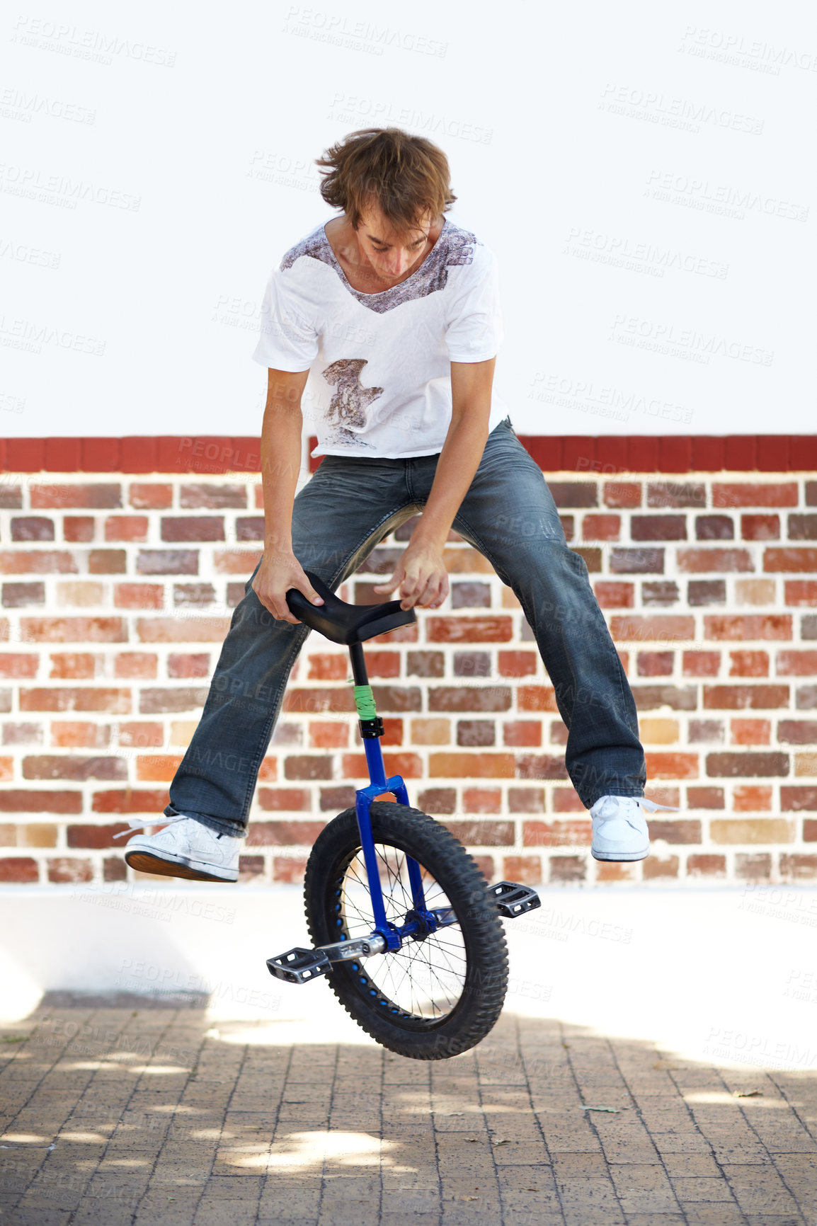 Buy stock photo Unicycle, sports and man jumping in city for exercise, training or workout on wall mockup space. Action, cycling and performance of stunt in street for trick, travel and eco friendly transportation.