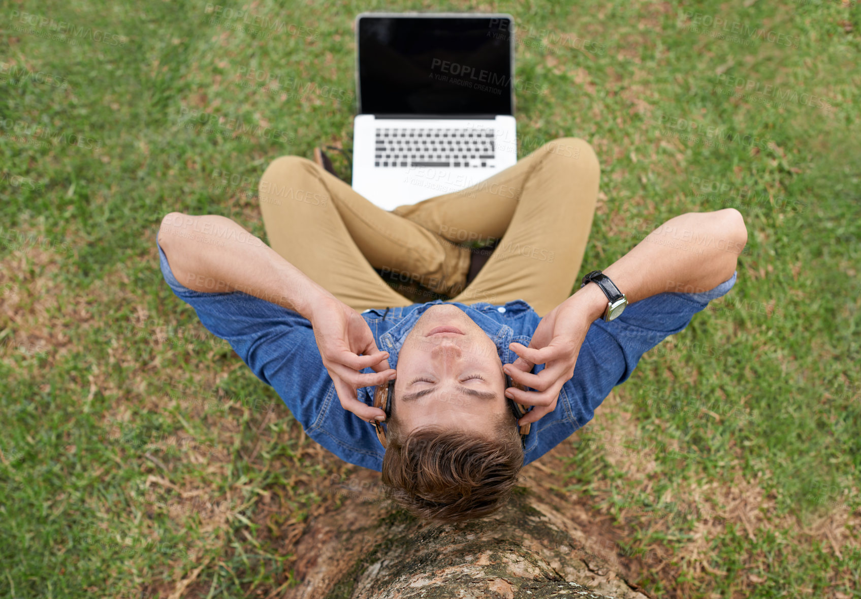 Buy stock photo Man, headphones and music in park with laptop streaming podcast or radio under tree outdoor. Person, aerial view and listening to sound on grass or relax with calm audio for work in woods or backyard
