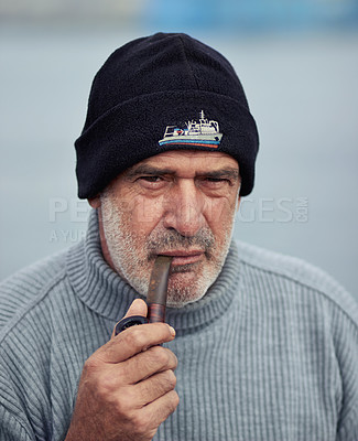 Buy stock photo Fisherman portrait, mature and man with smoking pipe by nature at a port for fishing. Old man face, elderly and senior dock worker sitting outdoor with tobacco smoke product at a harbor for work