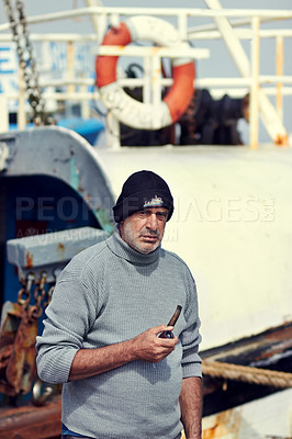 Buy stock photo Fisherman boat, mature man portrait and smoking pipe by the sea water at a port for fishing. Old man, ocean and senior dock worker sitting by boats outdoor with tobacco smoke at a harbor for work