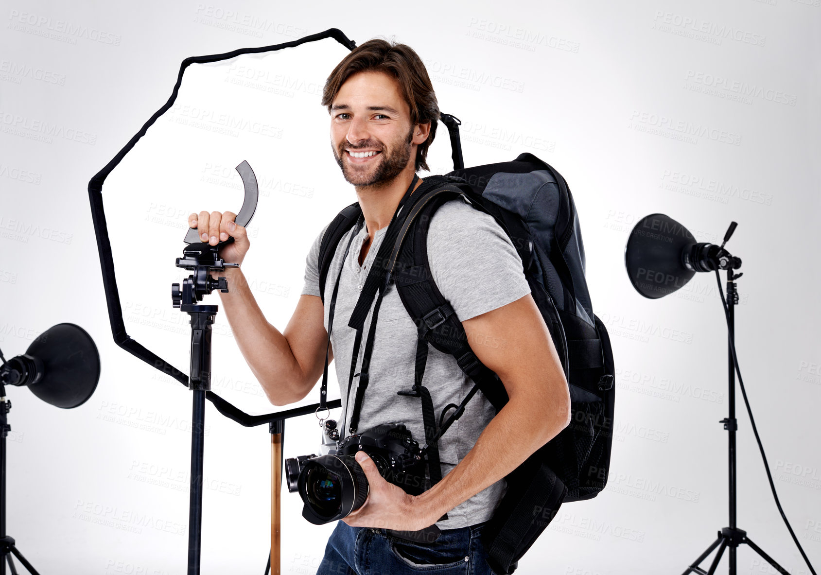 Buy stock photo Photographer, backpack and happy with camera in studio for career, behind the scenes and equipment. Photography, person or smile with lighting, confidence and shooting gear for photoshoot or passion