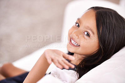 Buy stock photo Happy, wave and portrait of child on sofa for playful, fun and rest on weekend in living room. Smile, childhood and face of young girl alone on couch for relaxing, comfortable and free time in home