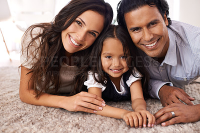 Buy stock photo Happy family, portrait and lying on floor for love, bonding or care together at home. Face of mother, father and little girl, daughter or child with smile in living room for holiday weekend at house