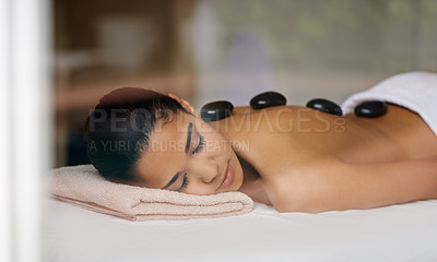Buy stock photo Shot of a young woman enjoying a hot rock treatment at a spa