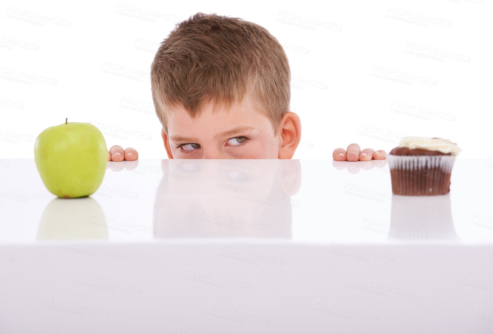 Buy stock photo Apple, cake and choice with a boy deciding between sweets or health in studio on a white background. Food, fruit and decision with a male child choosing a healthy snack or a cupcake on blank space