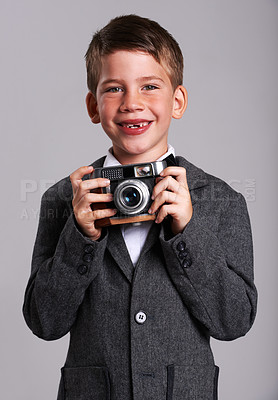 Buy stock photo Studio shot of a young boy in an old suit holding a vintage camera