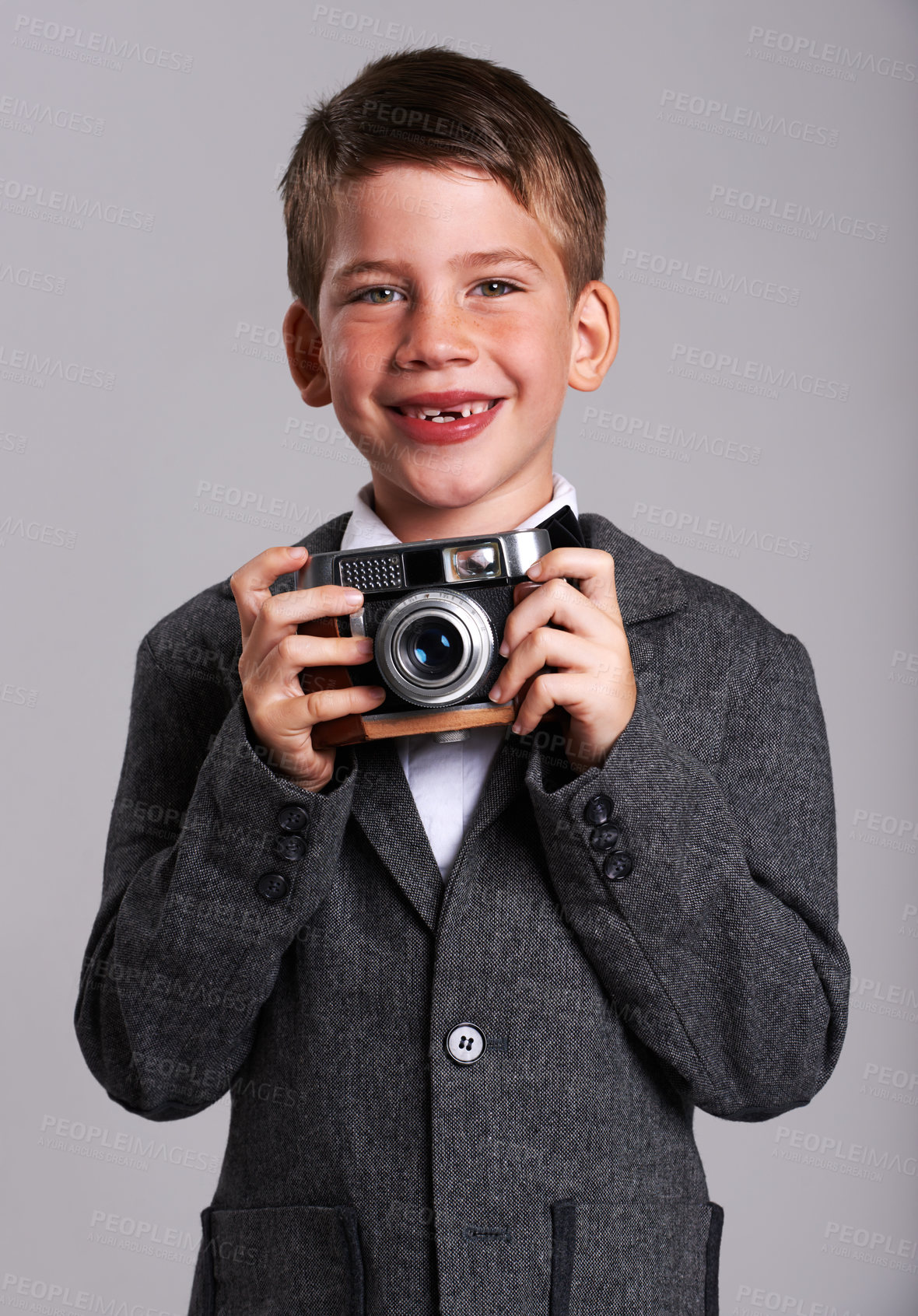 Buy stock photo Studio shot of a young boy in an old suit holding a vintage camera