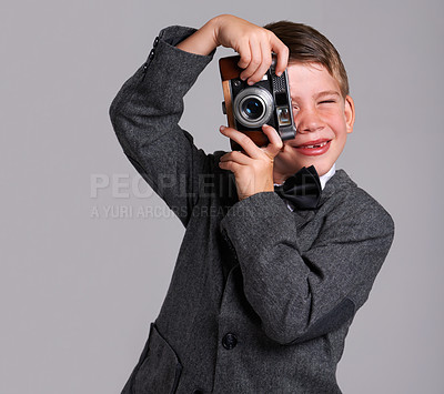 Buy stock photo Camera, photography and boy child in studio in elegant, classy or fancy suit outfit with smile. Happy, vintage and young kid with dslr equipment for picture with bowtie for fashion by gray background