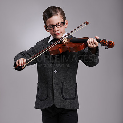 Buy stock photo Smile, music and kid with violin in studio for practice with suit and glasses for fashion. Happy, style and cute young boy child playing string instrument with spectacles by gray background.