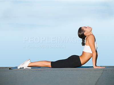 Buy stock photo Blue sky, fitness and woman on floor for yoga, workout and exercise outdoors for healthy body. Pilates training, cobra pose and female person stretching for wellness, flexibility or balance in nature