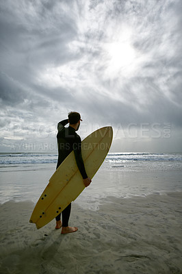 Buy stock photo Man, surfboard and adventure at beach on vacation, weekend and sports for fitness in water. Male person, back and cloudy sky for ocean waves, wetsuit and traveling on holiday or getaway for peace