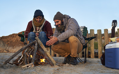 Buy stock photo Men, sunset and campfire with warming hands, smile and happy from travel adventure and journey outdoor. Friends, ocean and sea with bonding, hug and vacation by the beach on holiday with fire