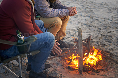 Buy stock photo Campfire, friends and hands of men by the beach at sunset with vacation and camping. Ocean, outdoor and together with travel and people in a trip and journey with warm fire and conversation by sea