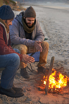 Buy stock photo Men, sunset and campfire with cold hands, smile and happy from travel adventure and journey outdoor. Friends, ocean and sea with bonding, nature and vacation by a beach together on holiday with fire