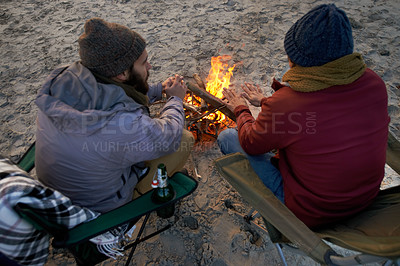 Buy stock photo Campfire, friends and talking with men by the beach at sunset with vacation and camping. Ocean, outdoor and together with travel and people back on trip and journey with fire and conversation by sea
