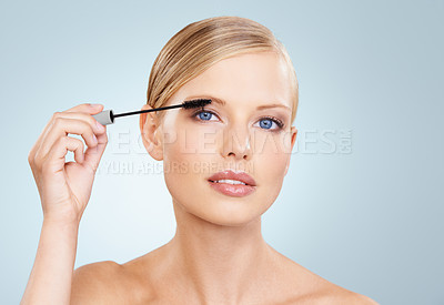 Buy stock photo Beauty, mascara and portrait of woman in studio with confidence, makeup for lashes or facial glow. Glamour, cosmetics and face of girl on blue background with healthy skin shine, brush and wellness.