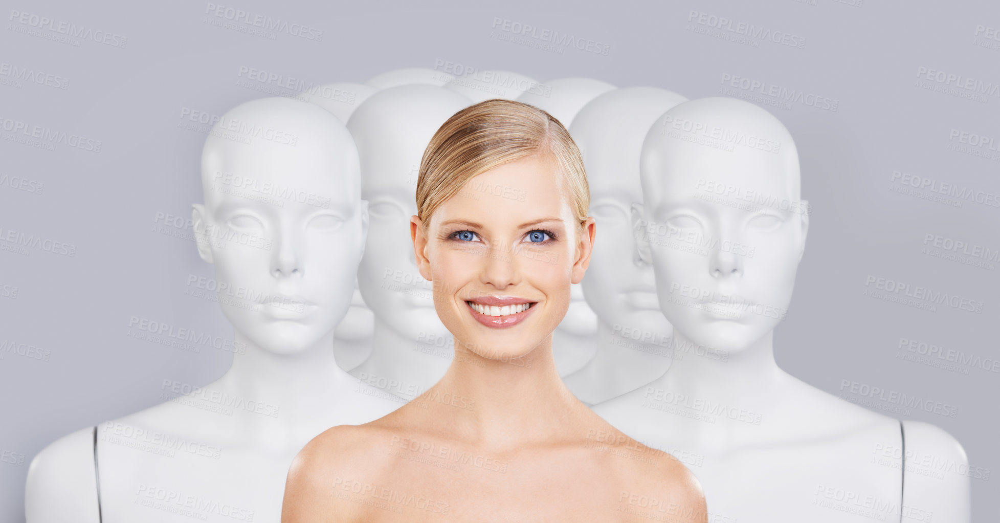 Buy stock photo A young woman standing amongst a group of mannequins