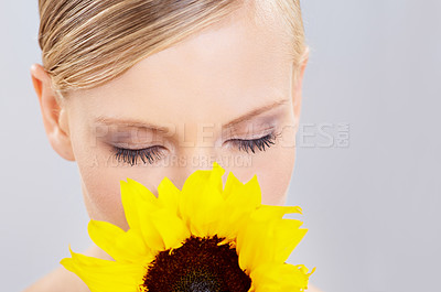 Buy stock photo Beauty, makeup and sunflower with natural woman in studio on gray background for spring or summer aroma. Face, skincare and young model smelling scent of flower at spa for cosmetics or dermatology