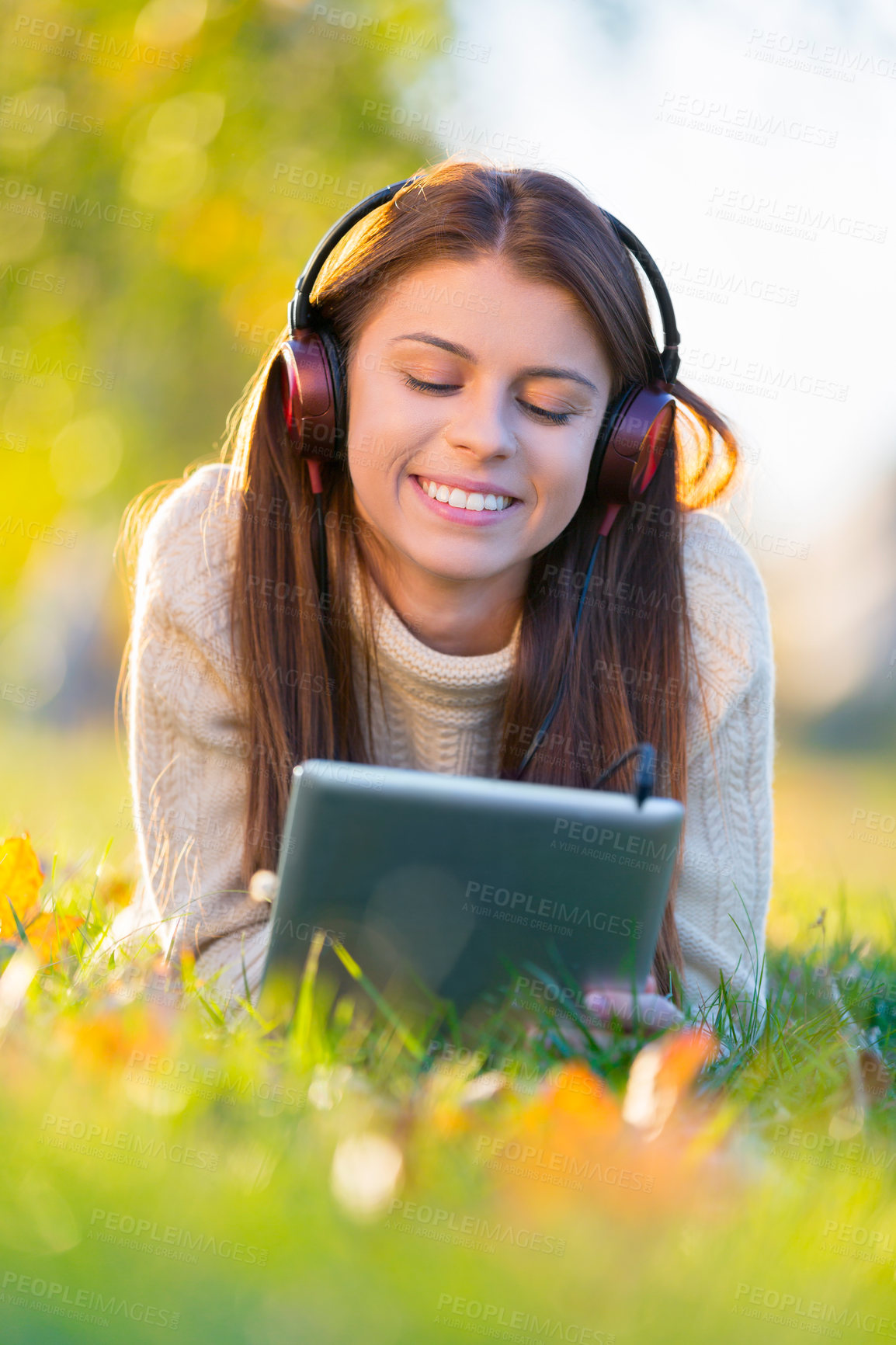 Buy stock photo Woman, headphones and tablet for music on grass, streaming radio and online games in outdoors. Female person, nature and internet for scrolling on social media on weekend, calm and peaceful song