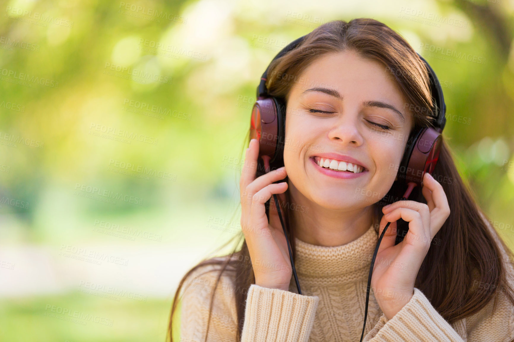 Buy stock photo An attractive young woman listening to music outdoors