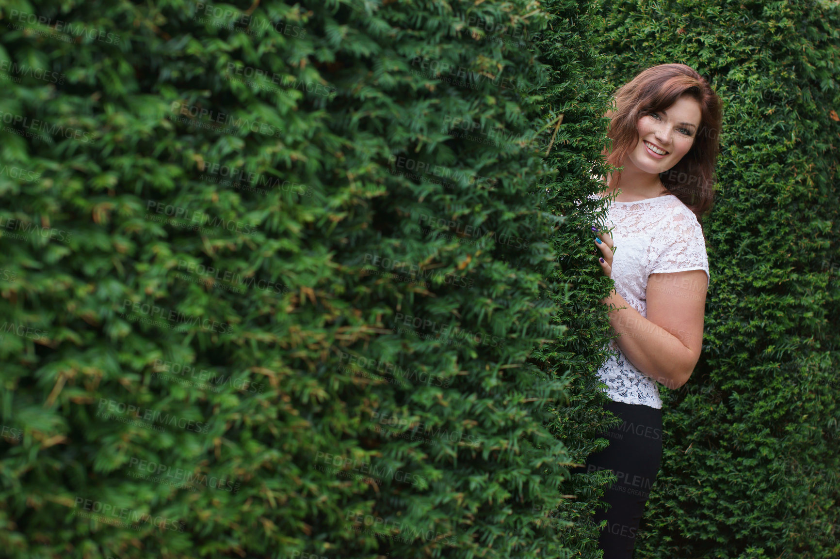 Buy stock photo Happy, portrait and a woman in a nature maze, enjoying environment and peeking from a hedge. Smile, beautiful and a young person by a bush or plants for playing, walking or outdoor weekend fun