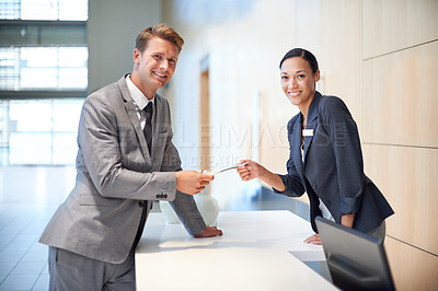 Buy stock photo Receptionist, businessman and hotel for customer support, hospitality and check in for travel with brochure. Corporate people, smile and paper at table for service, promotion or help at front desk