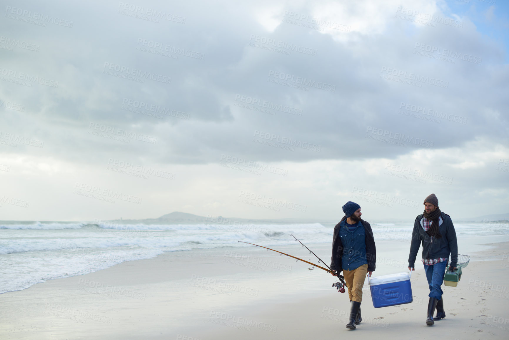 Buy stock photo Clouds, fishing and men walking at ocean together with cooler, tackle box and holiday in mockup space. Beach, fisherman and friends with rods, bait or tools at waves on winter morning vacation at sea