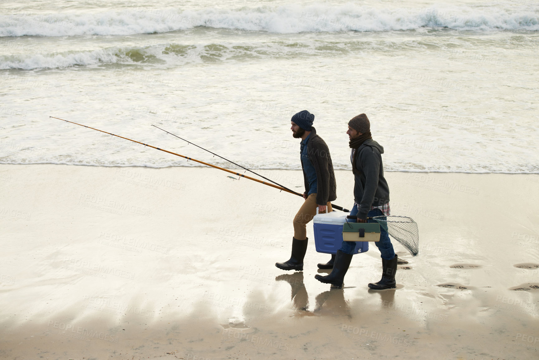 Buy stock photo Calm, fishing and men walking on beach together with cooler, tackle box and holiday conversation. Ocean, fisherman and friends with rods, bait and tools at waves on winter morning vacation at sea.