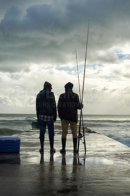 Buy stock photo Full length shot of two young men fishing at the ocean in the early morning