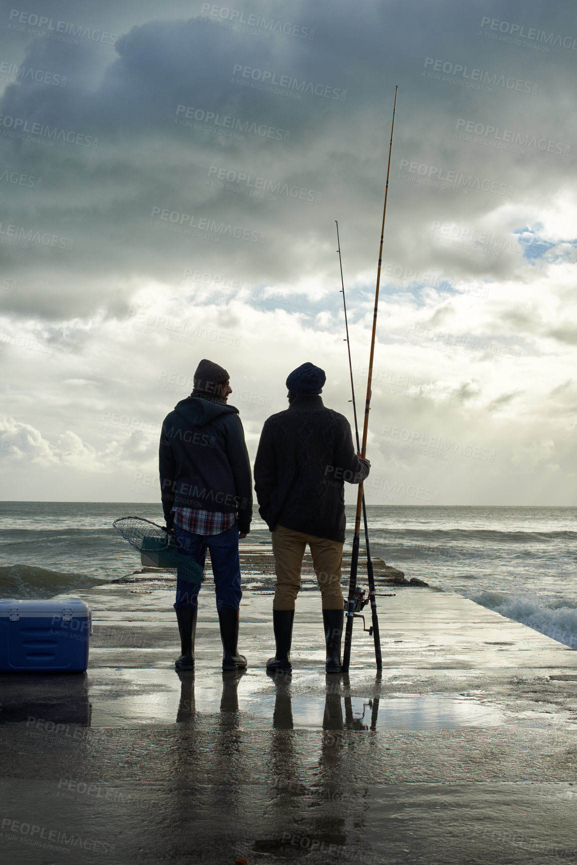 Buy stock photo Full length shot of two young men fishing at the ocean in the early morning