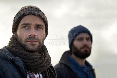 Buy stock photo Two handsome young fishermen standing on the beach on a cool morning