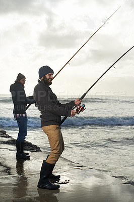 Buy stock photo People, fishing and friends with equipment at beach, relaxing and casting a line by ocean. Men, fisherman and together on vacation or holiday, hobby and bonding by waves and support on adventure