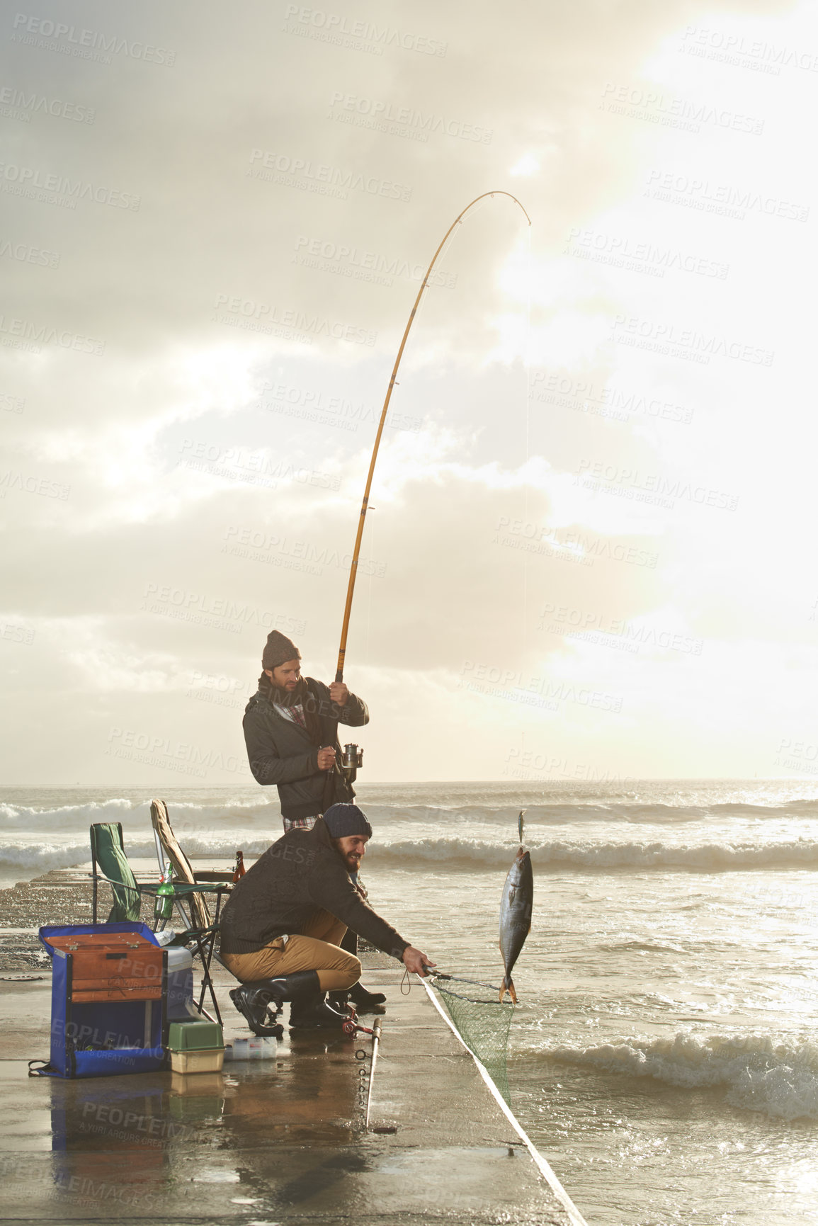 Buy stock photo Fishing, men and net with fish at pier with rod, waves and relax on vacation, holiday and adventure. Friendship, people and bonding in morning with overcast, sky and nature for activity and hobby