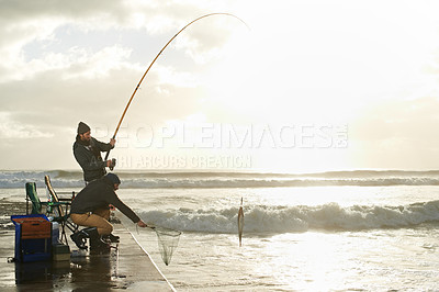Buy stock photo Shot of two young men fishing off a pier