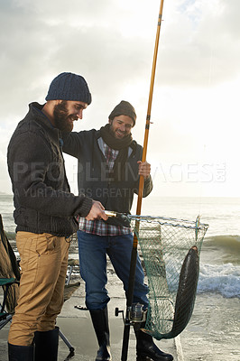 Buy stock photo Fishing, friends and net with fish at pier with rod, waves and relax on vacation, holiday and adventure. Friendship, men and bonding in morning with overcast, sky and nature for activity and hobby