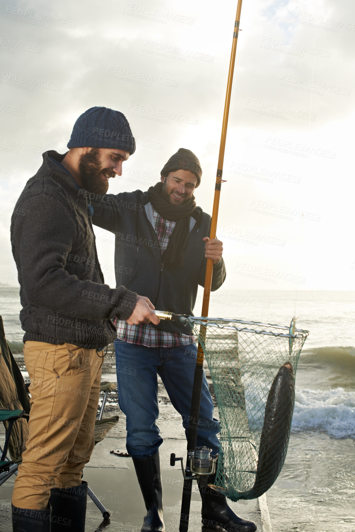 Buy stock photo Fishing, friends and net with fish at pier with rod, waves and relax on vacation, holiday and adventure. Friendship, men and bonding in morning with overcast, sky and nature for activity and hobby