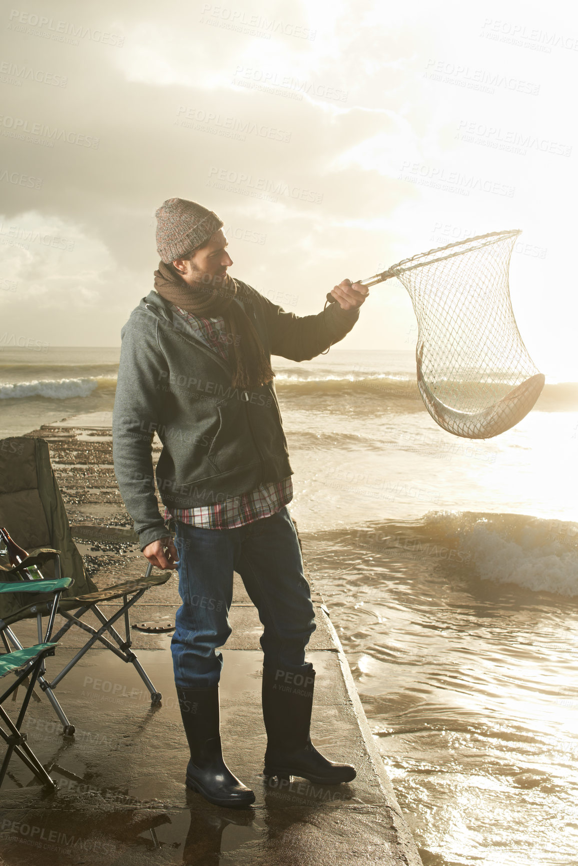 Buy stock photo Sunshine, net and beach with man, fish and hobby with equipment, waves and weekend break. Person, ocean and guy with tools for activity and happiness with shore, pier and seaside with lens flare
