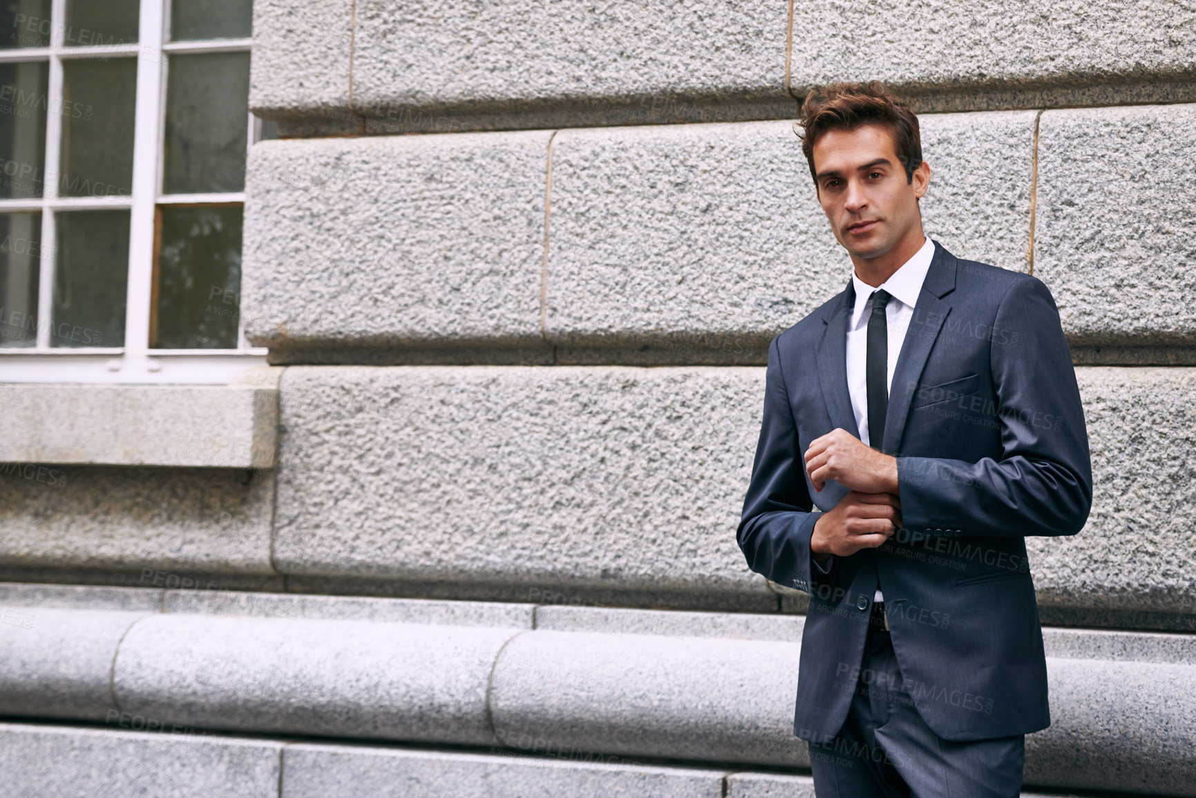 Buy stock photo Portrait of a handsome businessman in a suit standing outside a city building