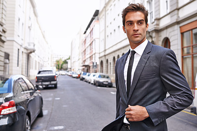 Buy stock photo A handsome businessman in a suit walking across a city street