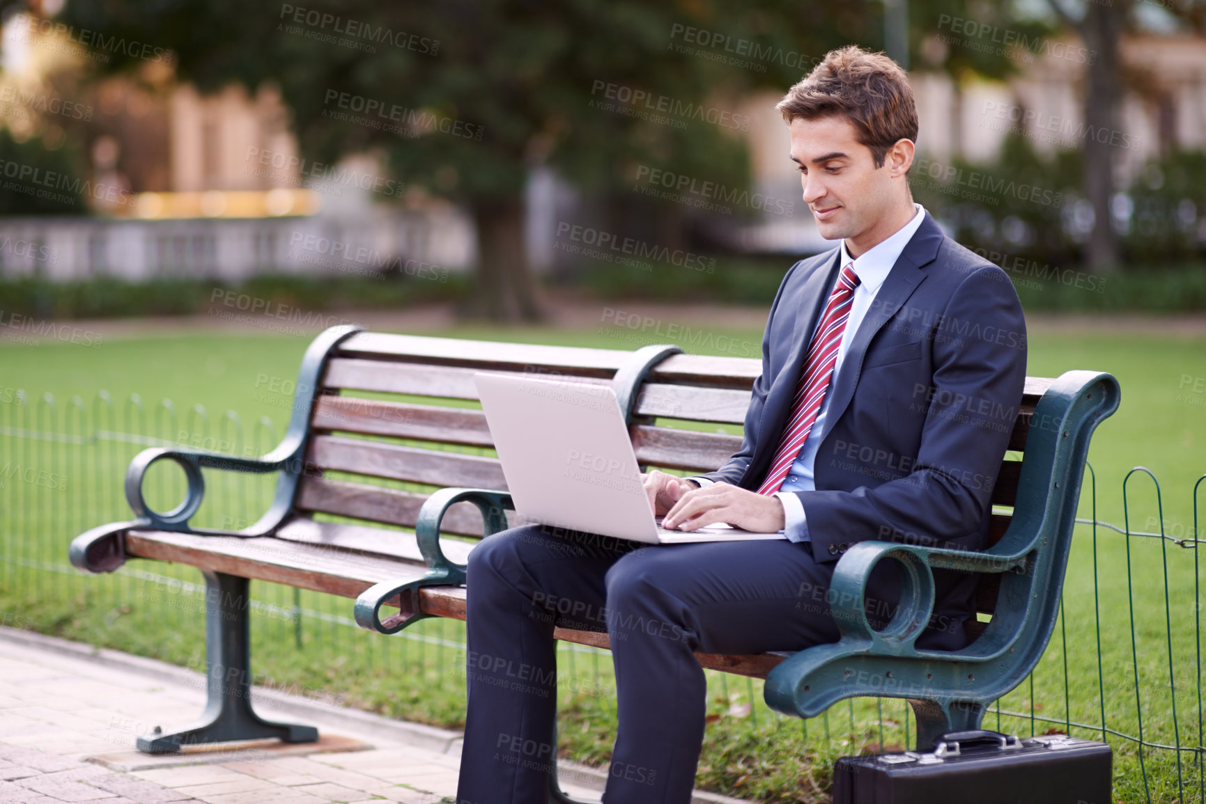 Buy stock photo Businessman, laptop and typing on park bench in nature for trading, checking email or outdoor networking. Man or trader in business suit on computer for communication or finance on outside furniture