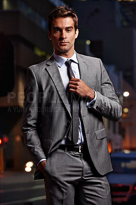 Buy stock photo Portrait of a handsome businessman in a suit standing in a city setting at night