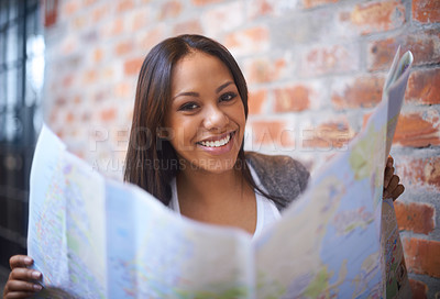 Buy stock photo Happy woman, portrait and reading map for travel, immigration or commute by a brick wall. Face of female person, tourist or traveler with smile for direction, geographic document or world coordinates